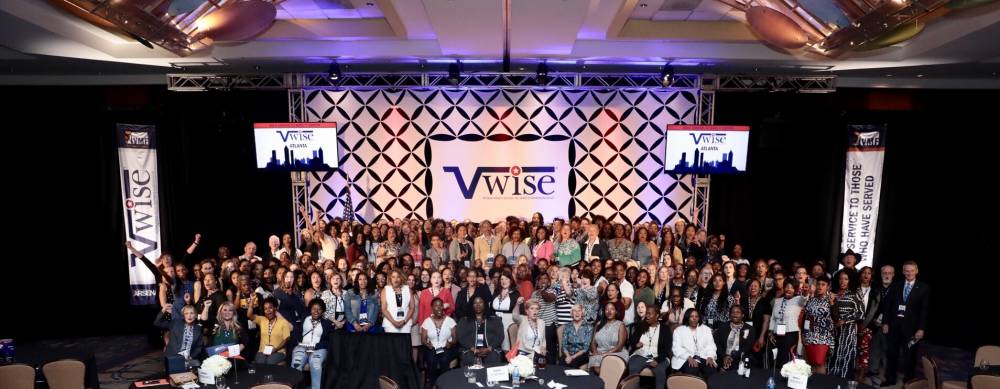 Large group of women standing and looking at the camera in large presentation hall