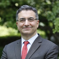 a man wearing grey suit and red tie with glasses