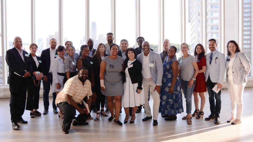 A group of people posing for a photograph in front of a large window.