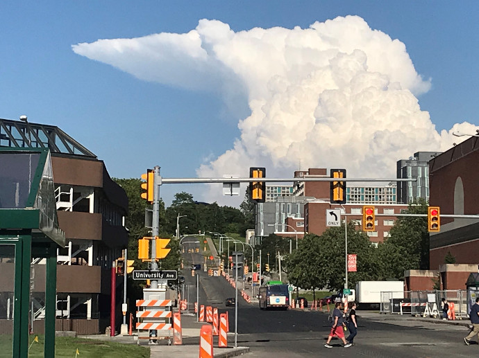 large cloud formation over city street and buildings