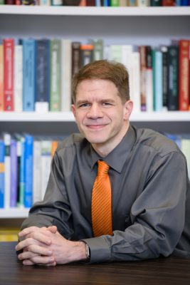 Man sitting in front of book shelf