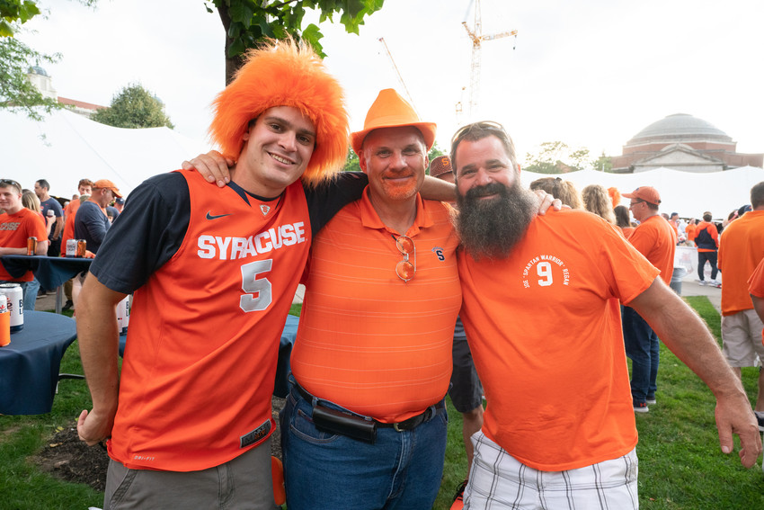 three men standing in field at tailgate