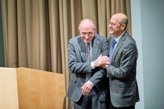 Dean David Perlmutter embraces Philip Needleman on stage.