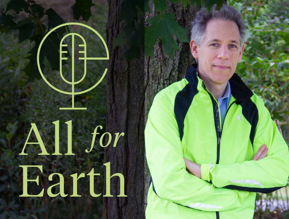 Ben Strauss leans against a tree in a forest