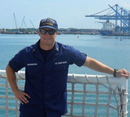 man in uniform leaning against a fence