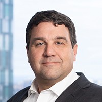 Headshot of Columbia Trustee Dean Dakolias, wearing a dark suit and white shirt