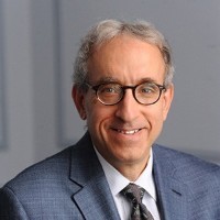 A bespectacled man smiling wearing a suit