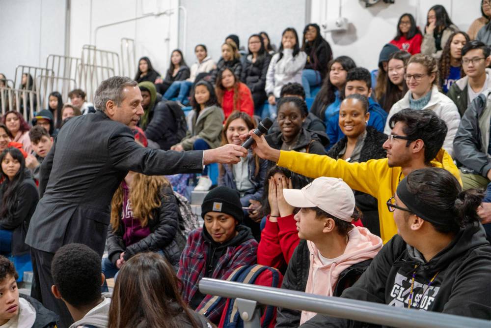 President Bacow handling a microphone to audience member.