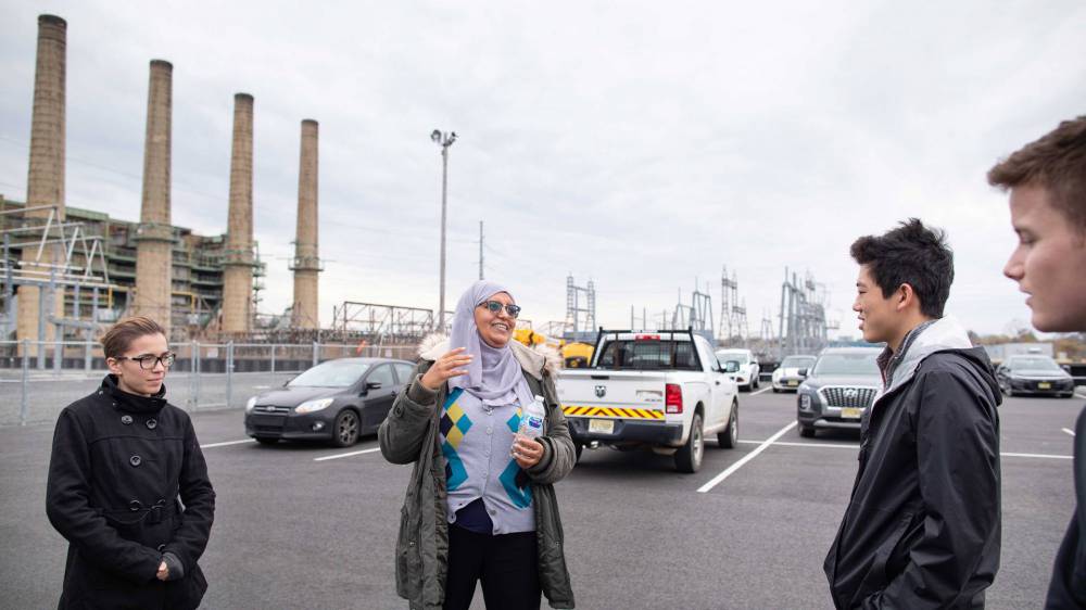 Assistant instructor speaks with students in the power plant parking lot