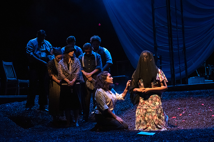 actors on stage—one wearing a dark veil in mourning