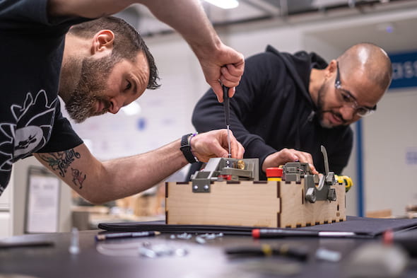 Danny Blacker, left, and Fernando Cruz, staffers at Rice University’s Oshman Engineering Design Kitchen, assemble a prototype of the ApolloBVM bag valve mask automation device. (Credit: Jeff Fitlow/Rice University)