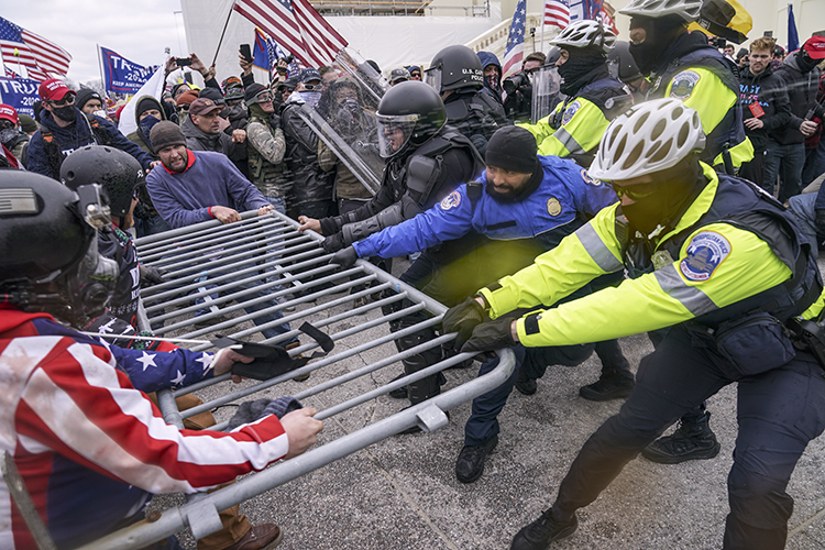 Trump supporters try to break through a police barrier while officers hold onto the barrier and pull it back